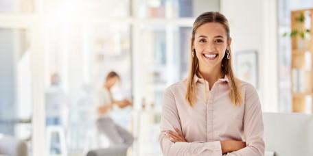 Junge Frau lächelt selbstbewusst am Arbeitsplatz