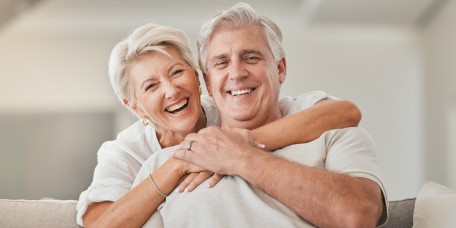 Seniorenpärchen umarmt sich lachend auf der Couch